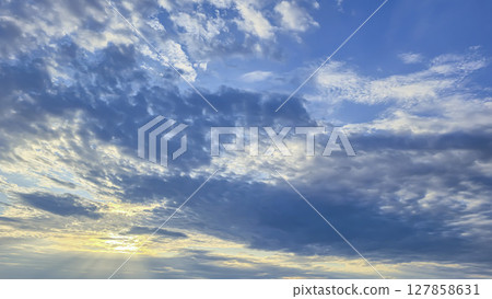 Dark blue sky with clouds over trees and water surface. Evening sunset. 127858631