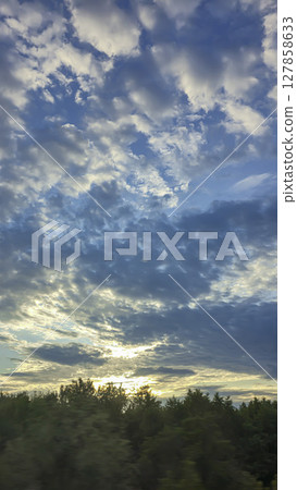 Dark blue sky with clouds over trees and water surface. Evening sunset. Dark blue sky with clouds over trees and water surface. Evening sunset. 127858633