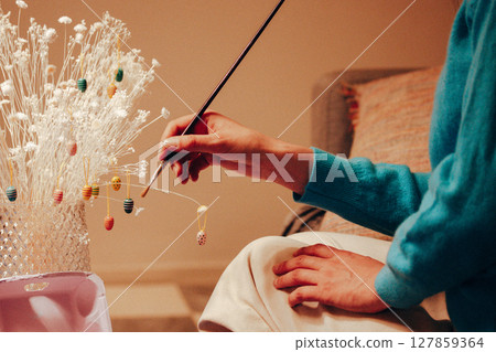 Colourful painted Easter eggs with a paint brush in a woman's hand. Authentic preparing decorations for the spring holidays in April. Home decor. 127859364
