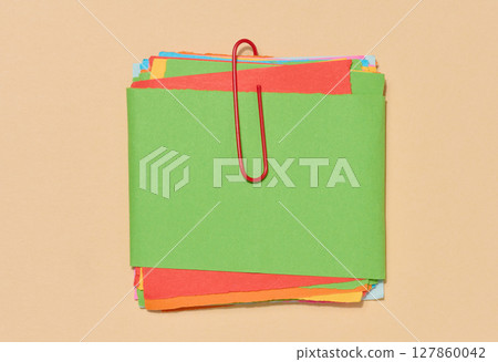 Stack of multi-colored sticky notes secured with a red paper clip, placed on a beige background. Stack of multi-colored sticky notes secured with a red paper clip, placed on a beige background. 127860042