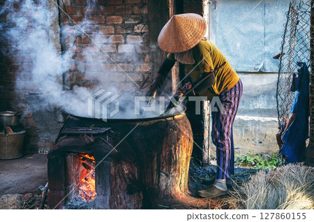 Vietnamese female worker works in a reed dyeing workshop at a wicker mat factory in a village in Vietnam 127860155