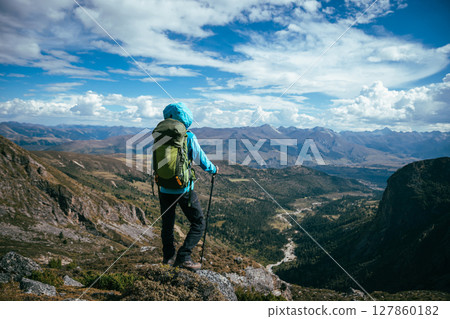 Backpacking woman climbing up on steep cliff edge at high altitude mountains top 127860182