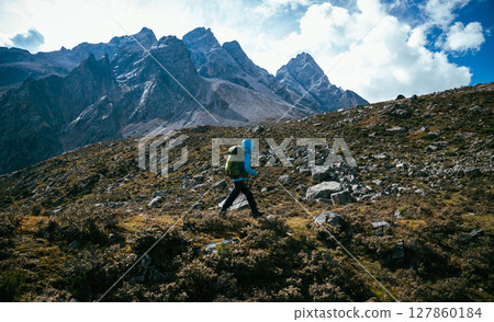 Backpacking woman climbing up at high altitude mountains top Backpacking woman climbing up at high altitude mountains top 127860184