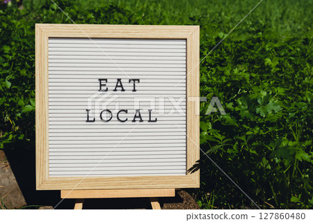 EAT LOCAL message on background of fresh eco-friendly bio grown green herb parsley in garden. Countryside food production concept. Locally produce harvesting. Sustainability EAT LOCAL message on background of fresh eco-friendly bio grown green herb parsley in garden. Countryside food production concept. Locally produce harvesting. Sustainability 127860480