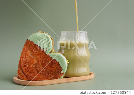Green tea Matcha latte cappuccino beverage Morning breakfast gift idea Heart shaped pistachio croissant on green background with copy space. Puff pastry trendy sweet dessert bakery. Creamy dough Green tea Matcha latte cappuccino beverage Morning breakfast gift idea Heart shaped pistachio croissant on green background with copy space. Puff pastry trendy sweet dessert bakery. Creamy dough 127860544