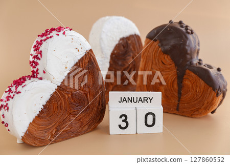 30 January National Croissant Day holiday calendar date celebration greeting card Heart shaped dark chocolate flavor croissant on beige background with copy space. Puff pastry new trendy sweet dessert 30 January National Croissant Day holiday calendar date celebration greeting card Heart shaped dark chocolate flavor croissant on beige background with copy space. Puff pastry new trendy sweet dessert 127860552