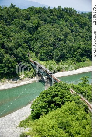 Limited Express Inaji (373 series) running along the Tenryu River with its fresh greenery 127861753