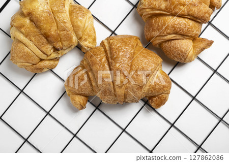 Freshly baked croissants on a cooling tray with a white background. Top view 127862086
