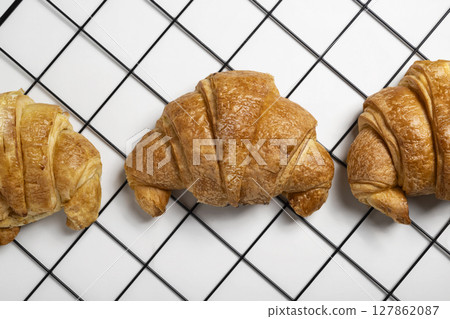 Freshly baked croissants on a cooling tray with a white background. Top view Freshly baked croissants on a cooling tray with a white background. Top view 127862087