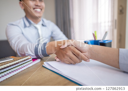 Indonesian southeast asian business people with paperwork meeting and handshake after reaching an agreement in teamwork for partnership or collaboration. Team collaboration and meetings concept Indonesian southeast asian business people with paperwork meeting and handshake after reaching an agreement in teamwork for partnership or collaboration. Team collaboration and meetings concept 127862913