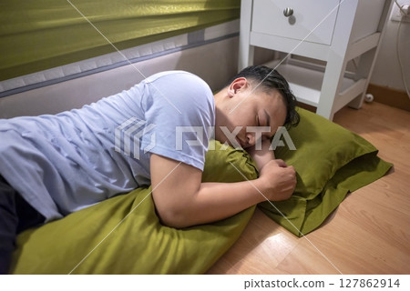 Indonesian southeast asian husband sleeping separately from his wife in the bedroom. Having a crisis and difficulties in a relationship Indonesian southeast asian husband sleeping separately from his wife in the bedroom. Having a crisis and difficulties in a relationship 127862914
