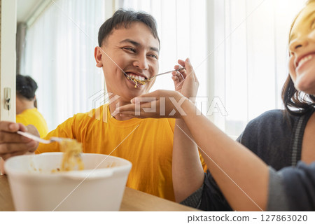 Indonesian southeast asian couple family eating noodles meal together in the dining room Indonesian southeast asian couple family eating noodles meal together in the dining room 127863020