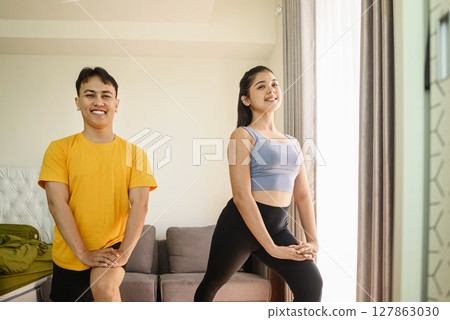 Indonesian southeast asian couple stretching before a workout at home for a healthy lifestyle and body care. Fitness and active lifestyles concept Indonesian southeast asian couple stretching before a workout at home for a healthy lifestyle and body care. Fitness and active lifestyles concept 127863030