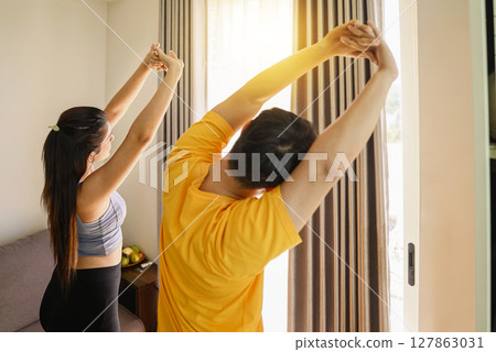 Indonesian southeast asian couple stretching before a workout at home for a healthy lifestyle and body care. Fitness and active lifestyles concept 127863031
