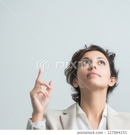 Young woman pointing upward in bright room 127864255