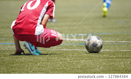 Youth soccer match (player taking free kick) 127864384