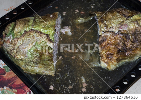 homemade big meat roll in Savoy cabbage green blanch leaves, oven-baked in baking tray full of its own juice. cut out pieces from the middle 127864610