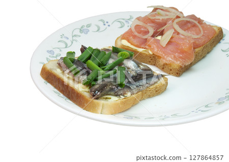 sandwich pair with slices of salted salmon and small silvery sprats, on white toast bread with butter, seasoned with chopped shallots. closeup. isolated on white background sandwich pair with slices of salted salmon and small silvery sprats, on white toast bread with butter, seasoned with chopped shallots. closeup. isolated on white background 127864857