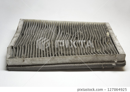 cabin air filter, wear out, dirty, with clogged deformed grid of carbon filtering media and foam rubber sealing strip on edge 127864925
