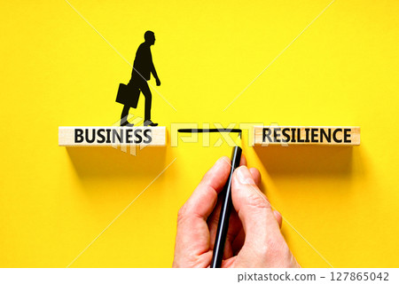 Business resilience symbol. Concept word Business resilience typed on wooden blocks. Beautiful yellow table yellow background. Businessman hand. Business and business resilience concept. Copy space. 127865042
