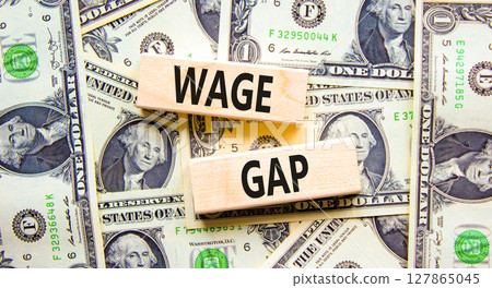 Wage gap symbol. Concept words Wage gap on wooden blocks on a beautiful background from dollar bills. Dollar bills. Business, support and wage gap concept. Copy space. Wage gap symbol. Concept words Wage gap on wooden blocks on a beautiful background from dollar bills. Dollar bills. Business, support and wage gap concept. Copy space. 127865045