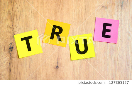 True symbol. Concept word True on beautiful colored paper. Beautiful wooden table wooden background. Business, lifestyle, support and true concept. Copy space. 127865157