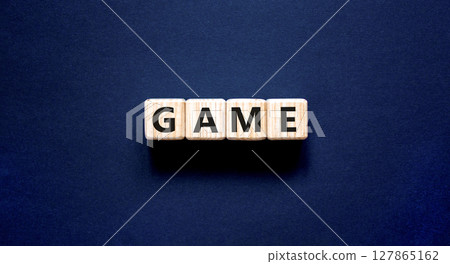 Game symbol. Concept word Game on beautiful wooden blocks. Beautiful black table black background. Business, lifestyle and game concept. Copy space. Game symbol. Concept word Game on beautiful wooden blocks. Beautiful black table black background. Business, lifestyle and game concept. Copy space. 127865162
