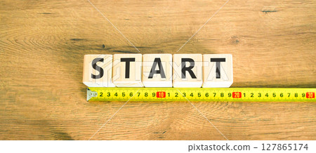 Start symbol. Concept word Start on beautiful wooden blocks. Beautiful wooden table wooden background. Beautiful yellow ruler. Business lifestyle start concept. Copy space. 127865174