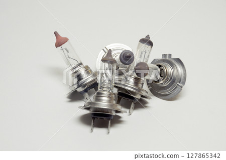 heap of used halogen lamps for automotive headlights, dual-contact connecting terminal 127865342