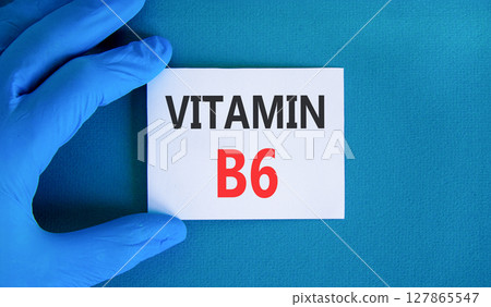 Vitamin B6 symbol. Concept words Vitamin B6 on beautiful white card. Doctor's hand in blue medical glove. Beautiful blue background. Medical healthy lifestyle Vitamin B6 concept. 127865547