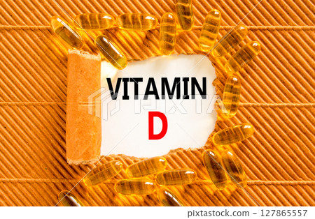 Vitamin D symbol. Concept words Vitamin D on beautiful white paper. Yellow pills tablets. Beautiful brown background. Medical healthy lifestyle Vitamin D concept. Vitamin D symbol. Concept words Vitamin D on beautiful white paper. Yellow pills tablets. Beautiful brown background. Medical healthy lifestyle Vitamin D concept. 127865557