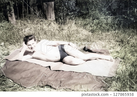 Vintage portrait of a young guy basking in the sun in the forest. Retro photo from 1962. Vintage portrait of a young guy basking in the sun in the forest. Retro photo from 1962. 127865938