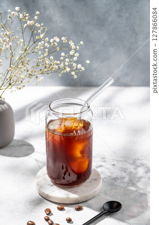 Cold brew coffee in a glass with ice on a light background with coffee beans 127866084