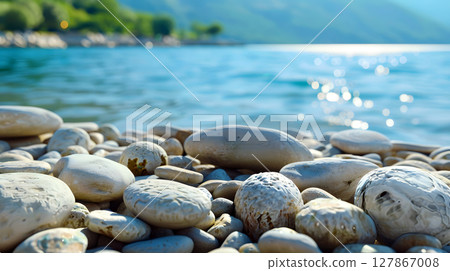 pebbles by a sparkling blue lake under clear sky 127867008