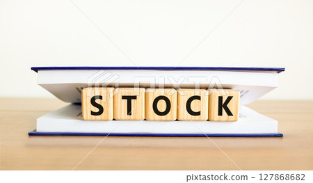 Stock symbol. Concept word Stock on beautiful wooden blocks in book. Beautiful wooden table white background. Business lifestyle stock concept. Copy space. 127868682