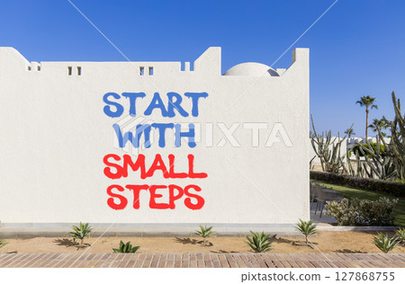 Start with small steps symbol. Concept words phrase Start with small steps on beautiful white wall. Beautiful white wall and blue sky background. Business Start with small steps concept. Copy space. 127868755