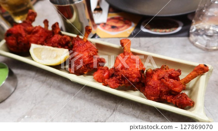 close up of Indian Tandoori chicken on a plate. A traditional dish made with marinated in yogurt and spices, roasted in a tandoor oven close up of Indian Tandoori chicken on a plate. A traditional dish made with marinated in yogurt and spices, roasted in a tandoor oven 127869070