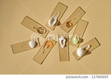 Samples of multi-colored cosmetic products on a beige background. 127869895
