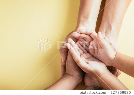 A studio shot with a top view angle showcasing family hands stacked against an isolated background. Parents and children hold an empty space reflecting support and love for Family and Parents Day. 127869920