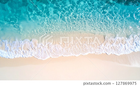 A view of the tropical blue sea from above: waves crashing on the white sand beach 127869975