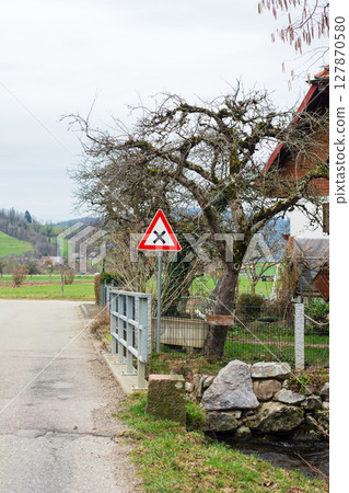 Warning sign indicating potential hazard near a rural road surrounded by lush green hills in a tranquil countryside setting during early spring mornings Warning sign indicating potential hazard near a rural road surrounded by lush green hills in a tranquil countryside setting during early spring mornings 127870580