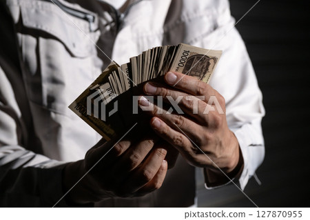 Man in work clothes holding money Man in work clothes holding money 127870955