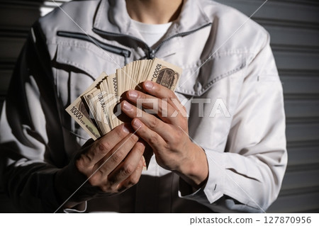 穿著工作服的男人拿著錢 127870956