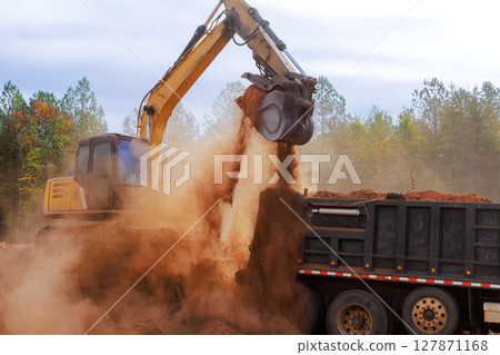 Heavy machinery moves dirt debris while creating construction site in wooded landscape under works day Heavy machinery moves dirt debris while creating construction site in wooded landscape under works day 127871168