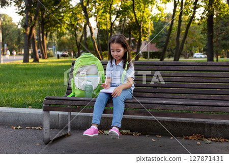 Young girl in park drawing with backpack and water bottle in autumn 127871431