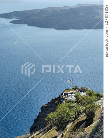 Greek flag on Santorini with a view of the sea and the nearby island 127871858
