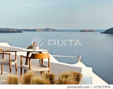 Cozy tables and chairs in a restaurant on the Greek island of Santorini with a view of the caldera 127871976