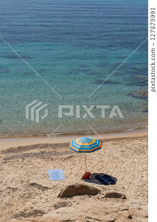 Colorful beach umbrella on empty shore 127873991