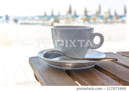 White coffee cup on beachside wooden table White coffee cup on beachside wooden table 127873999