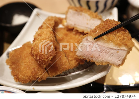 A close-up of a thickly sliced pork cutlet and assorted cabbage 127874974